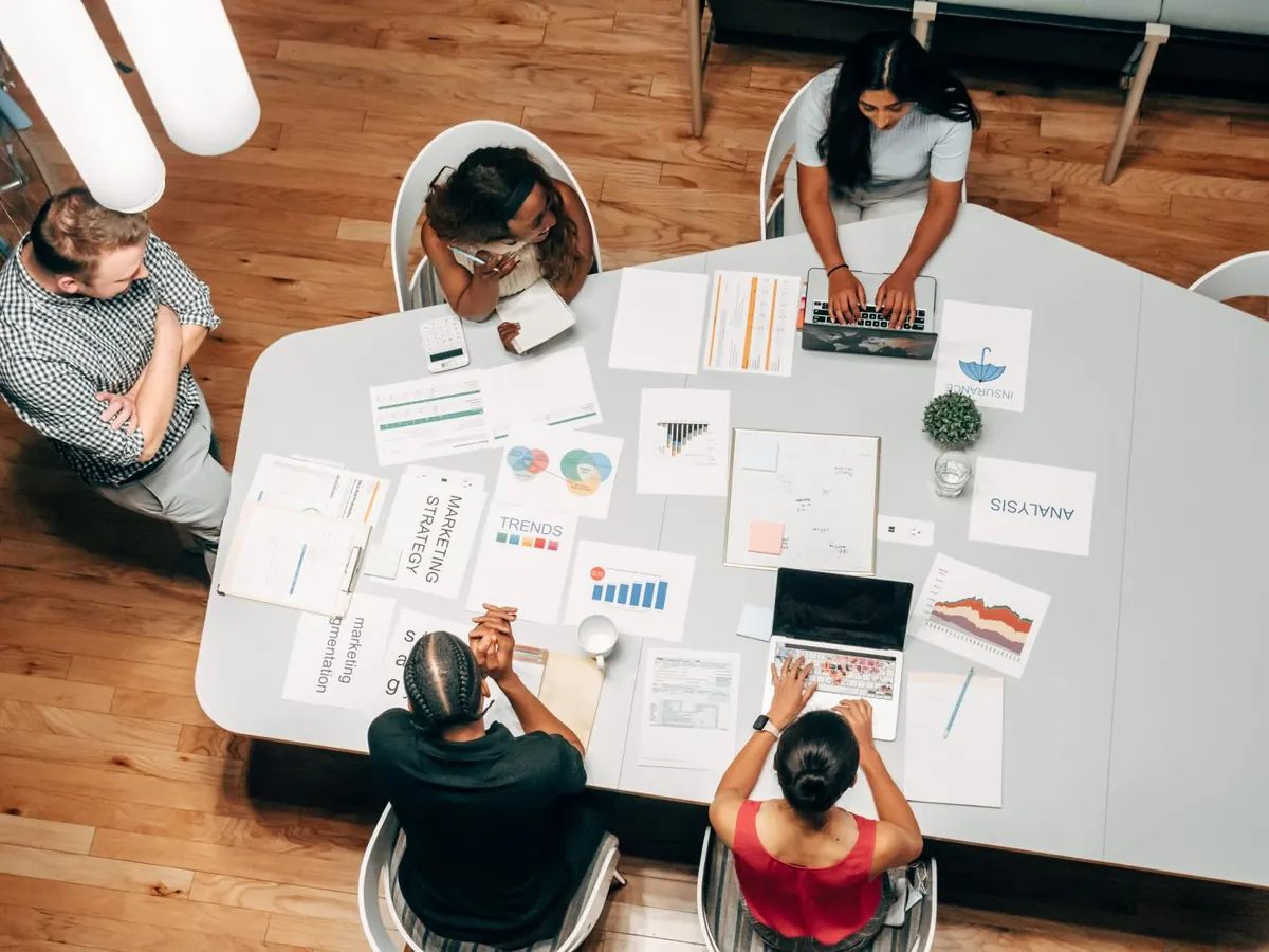 Team meeting around a large table covered with printed plans